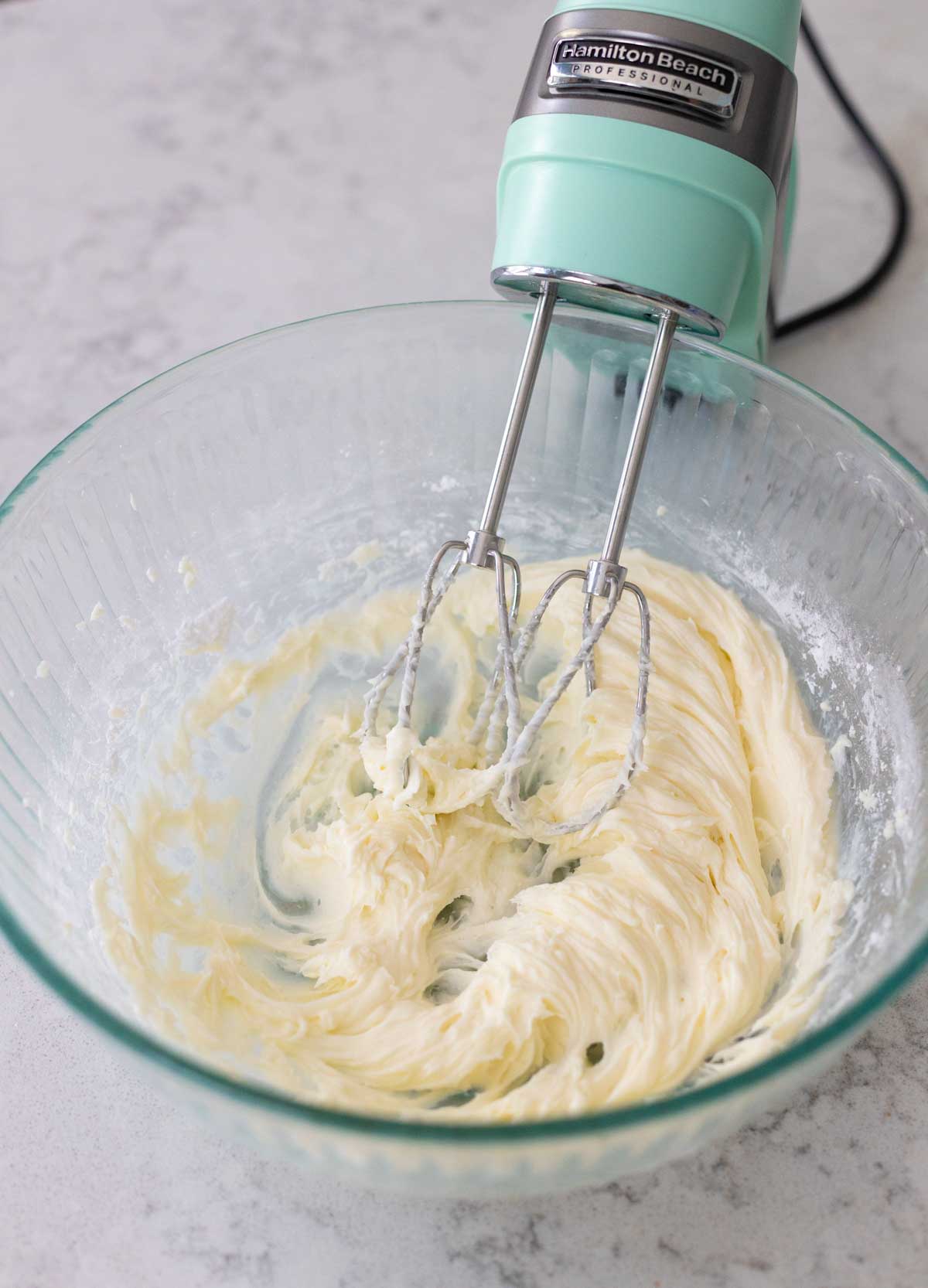 A hand mixer has whipped together the cream cheese and sugar.