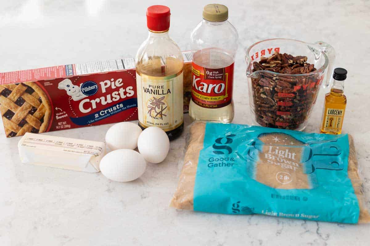 A store bought pie crust, sits next to the other basic pecan pie ingredients.