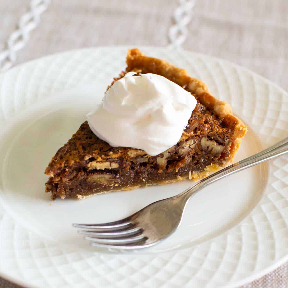 A slice of pecan pie has a dollop of Cool Whip on top.