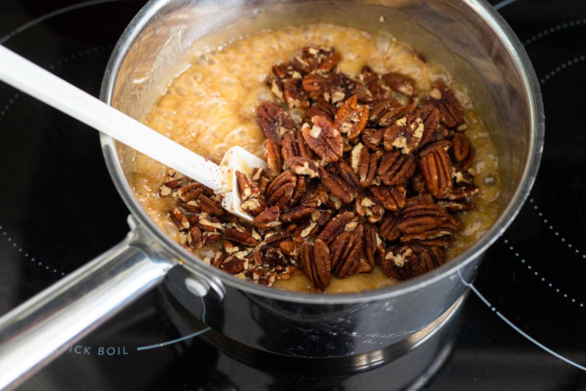 The pecans, bourbon, and vanilla have been added to the saucepan.