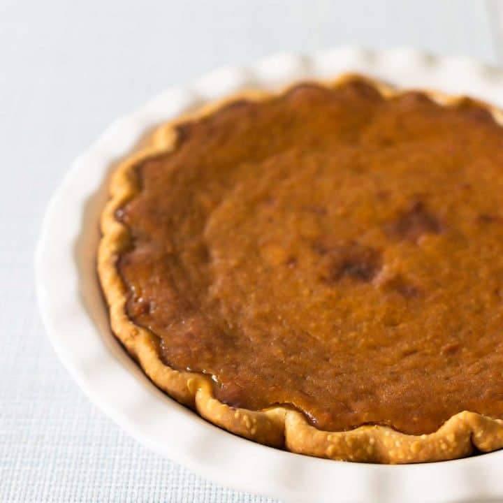 A pumpkin pie in a white pie plate.