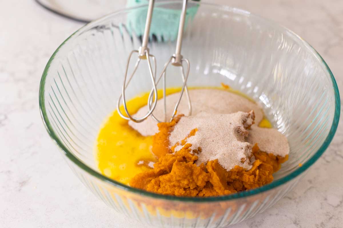The mixing bowl has eggs, pumpkin, and the spiced sugar.