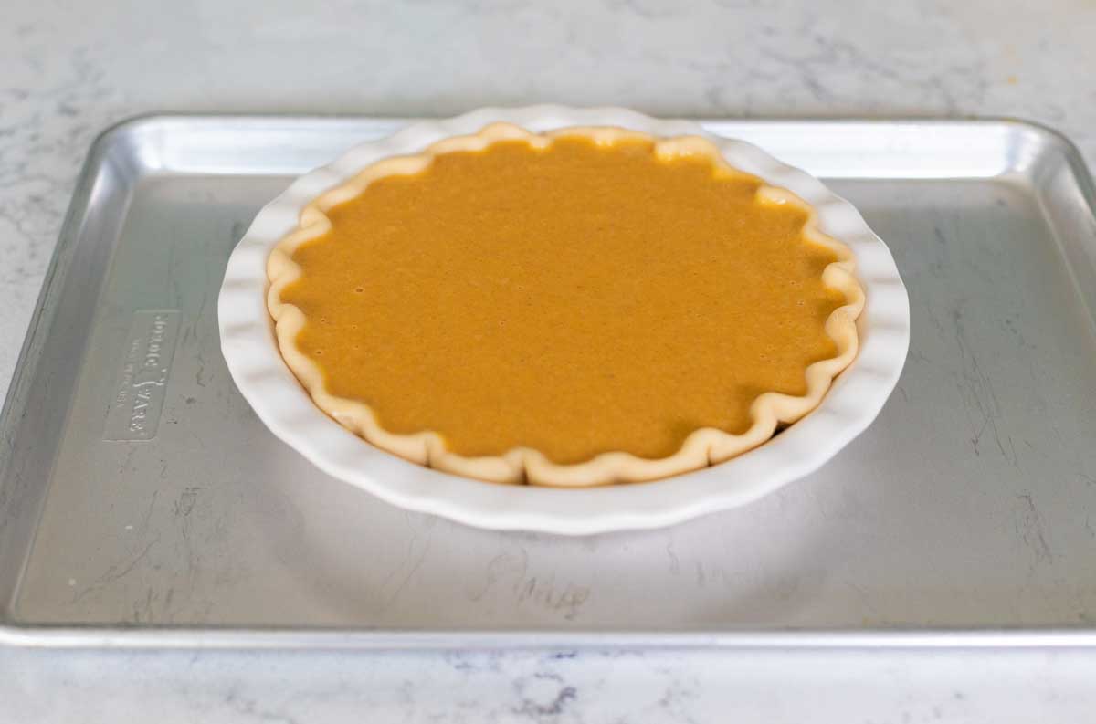 The filled pie crust is on a baking sheet, ready for the oven.