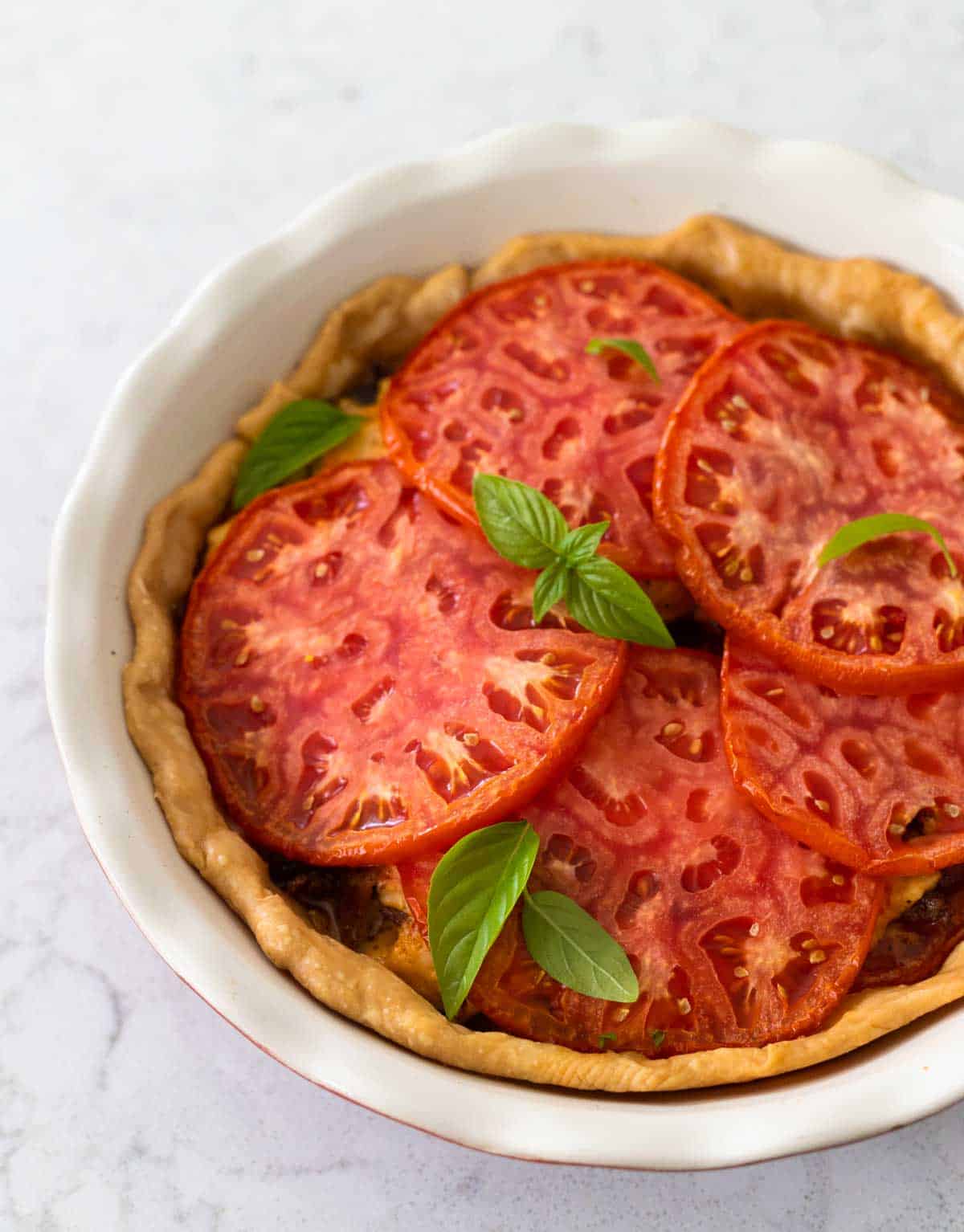 The baked tomato pie is cooled. It now has baby basil leaves sprinkled over the top.