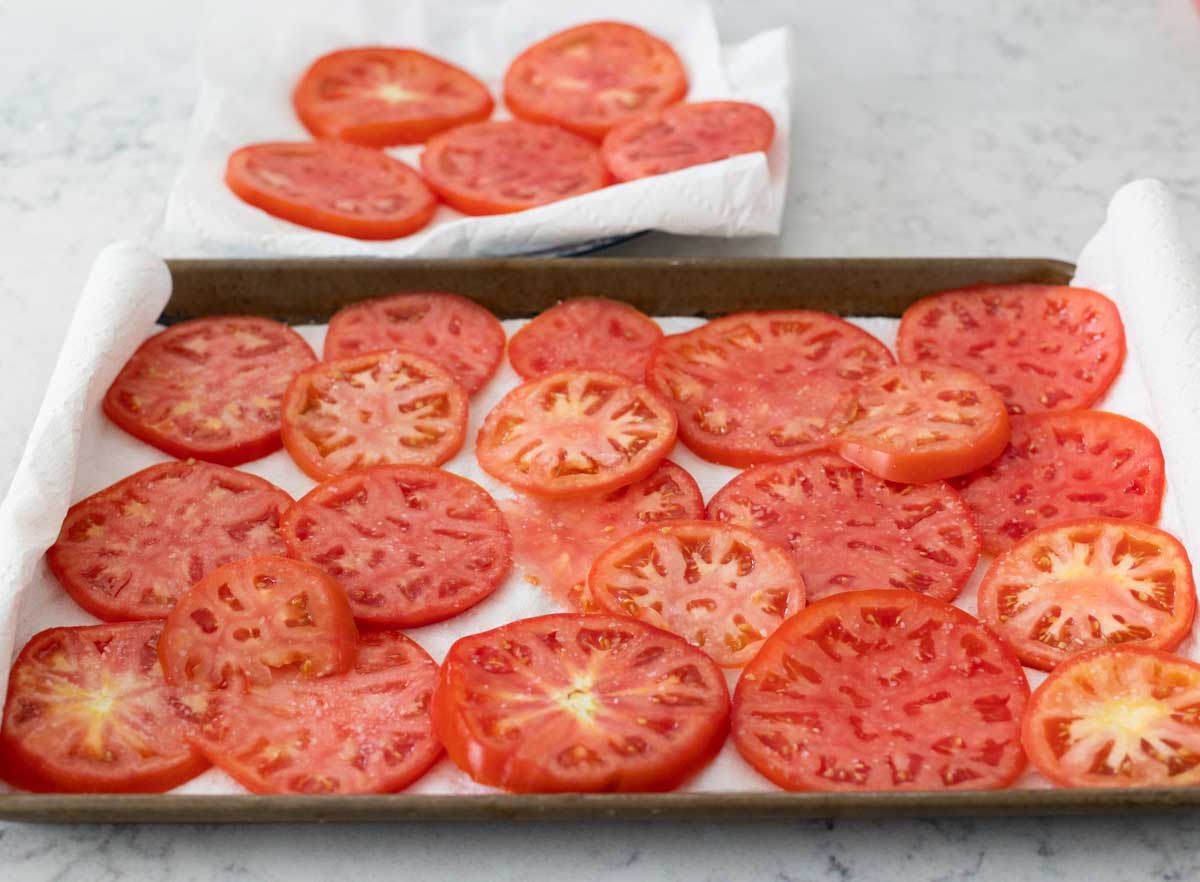 The slices of fresh tomato are draining on paper towels.