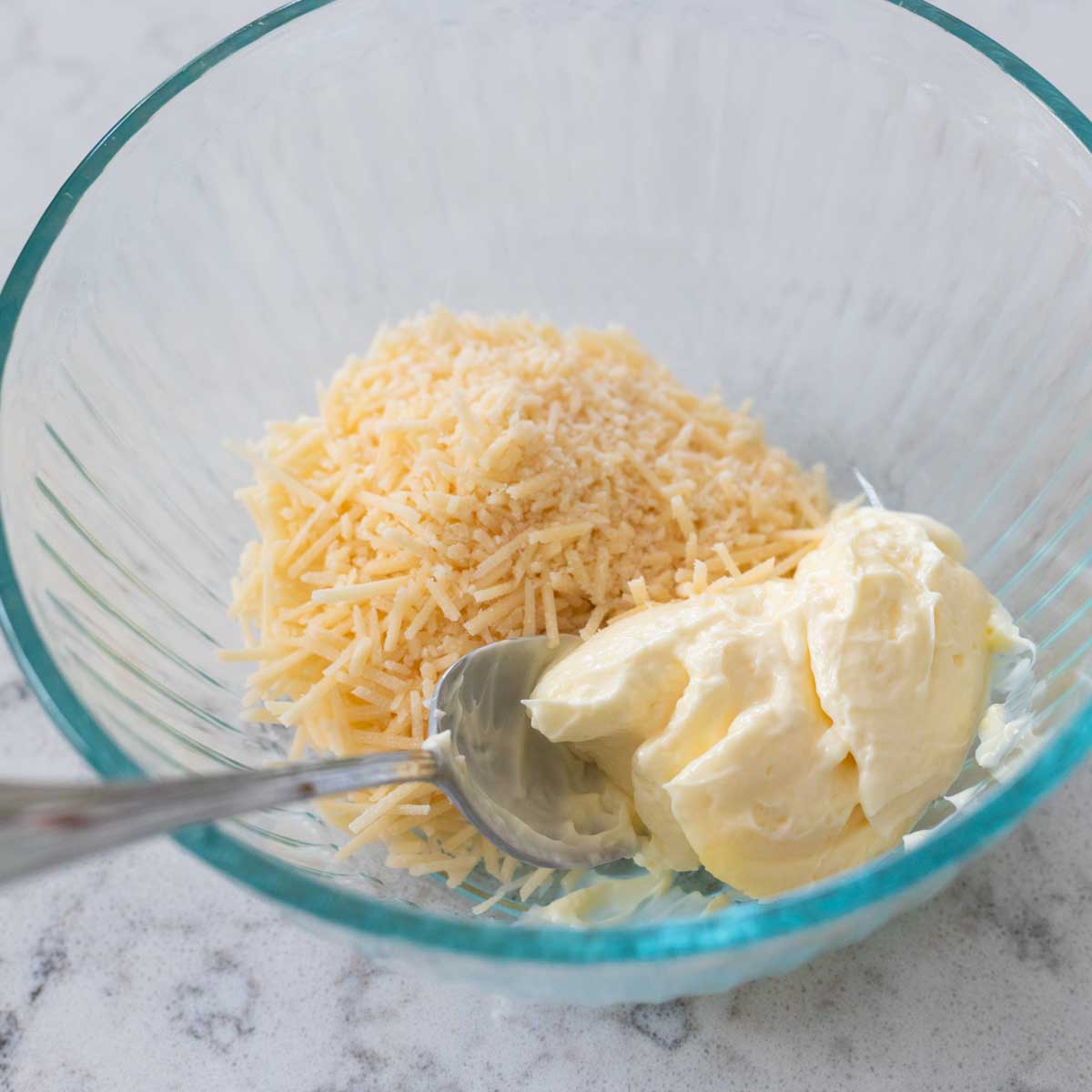 The mixing bowl has the mayo and parmesan being stirred together.