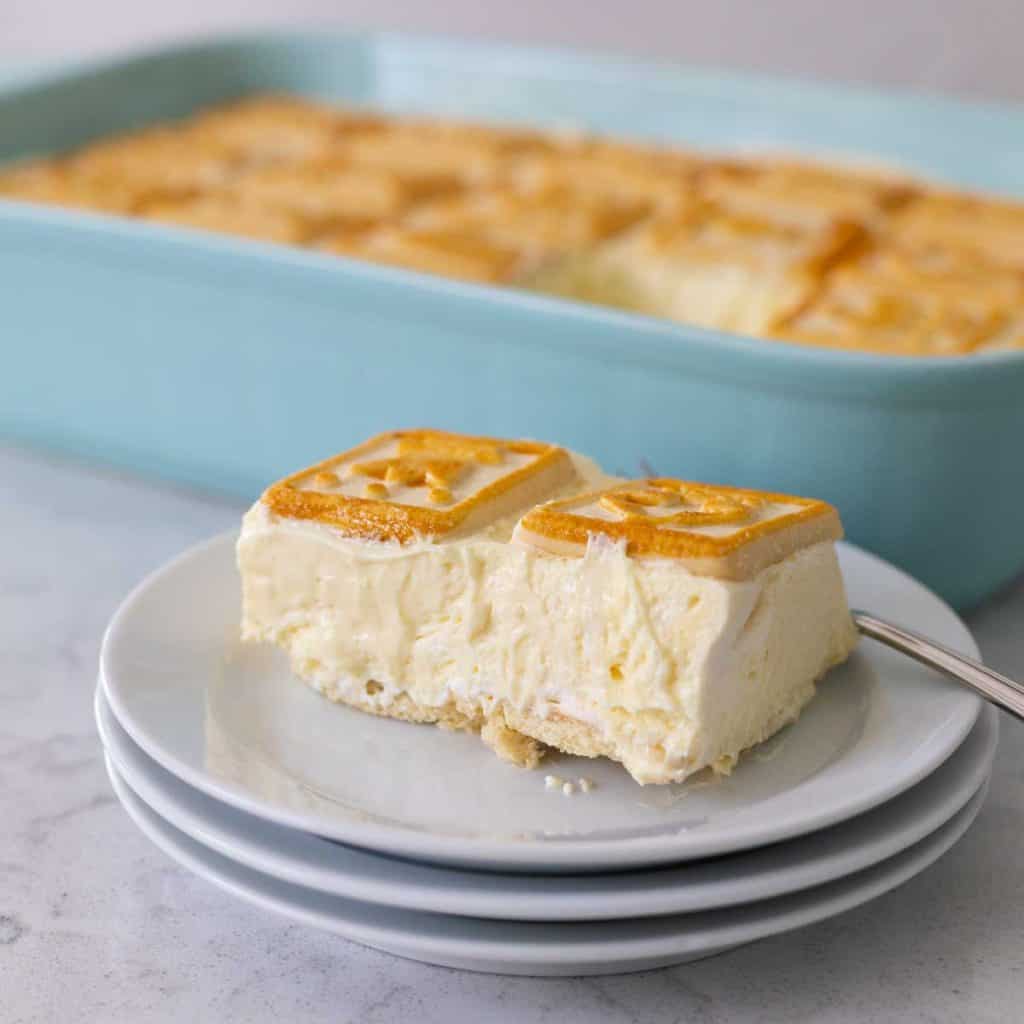 A slice of banana pudding sits on a stack of white plates. You can see that there are no bananas in the layers.