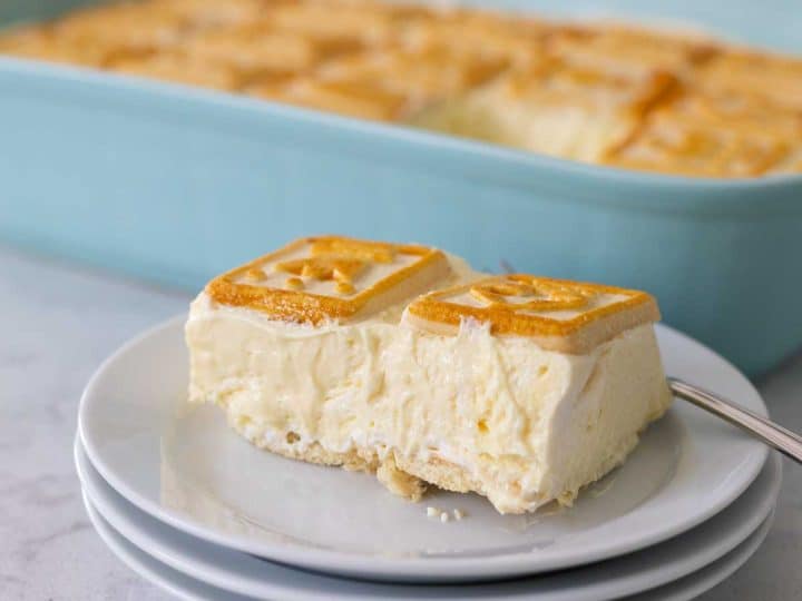 A slice of banana pudding sits on a stack of white plates. You can see that there are no bananas in the layers.