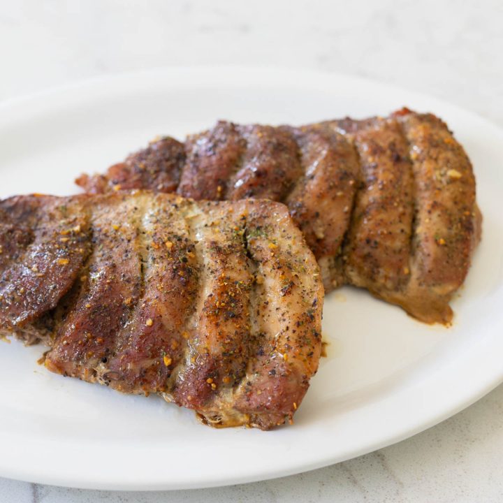 The white serving platter has two sets of baked boneless pork ribs coated in seasonings.