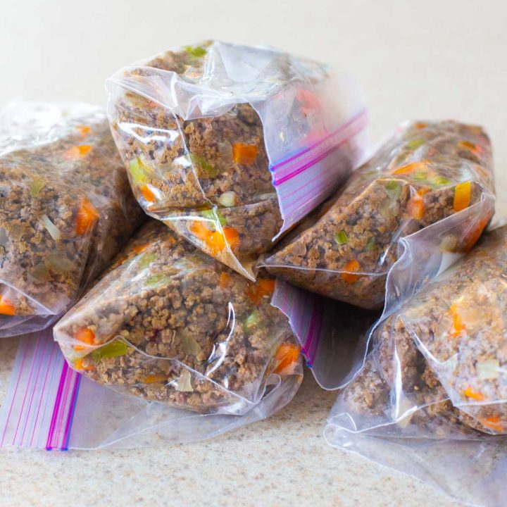 Batches of browned ground beef and vegetables are stored in plastic bags for the freezer.