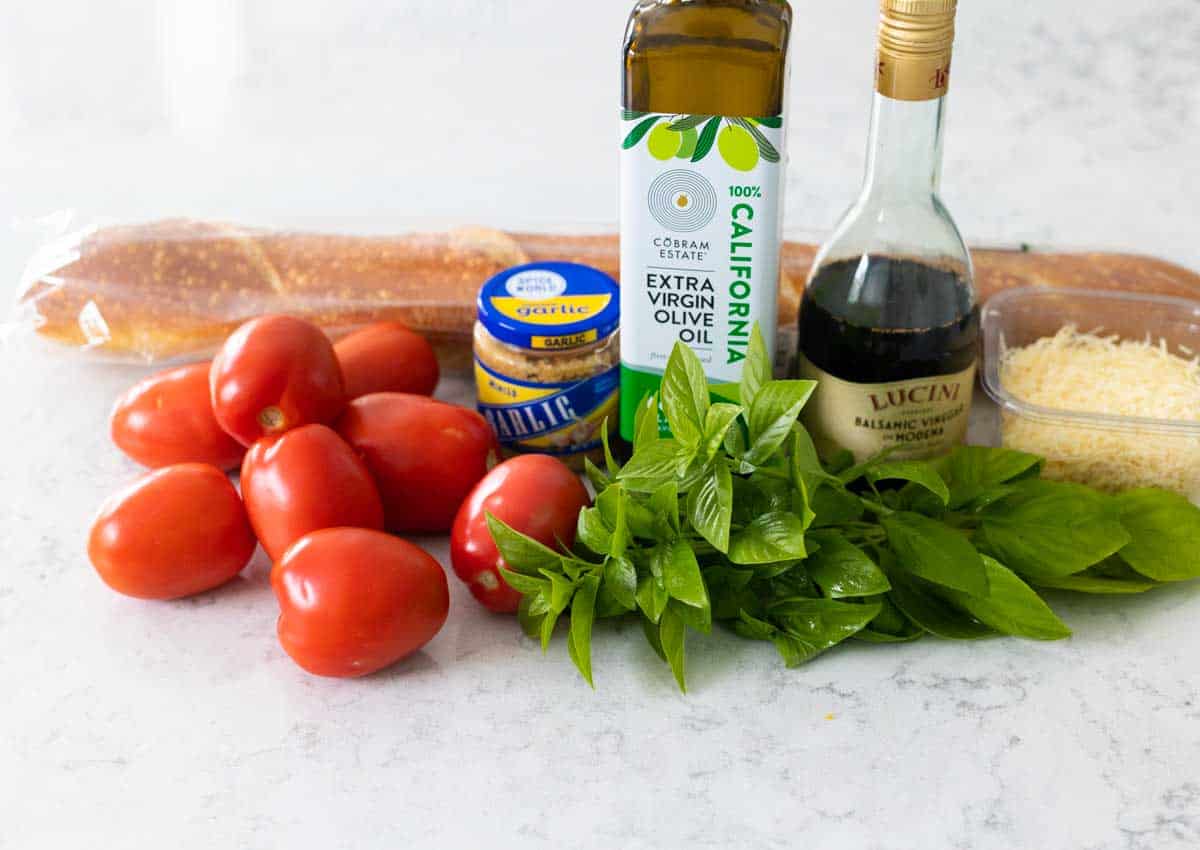 The fresh tomatoes, basil, bread, and other ingredients are on the counter.