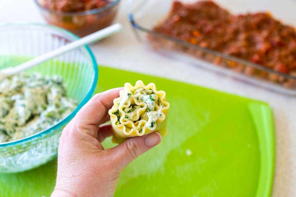 The lasagna roll-up is being held towards the camera so you can see the ruffled edges.