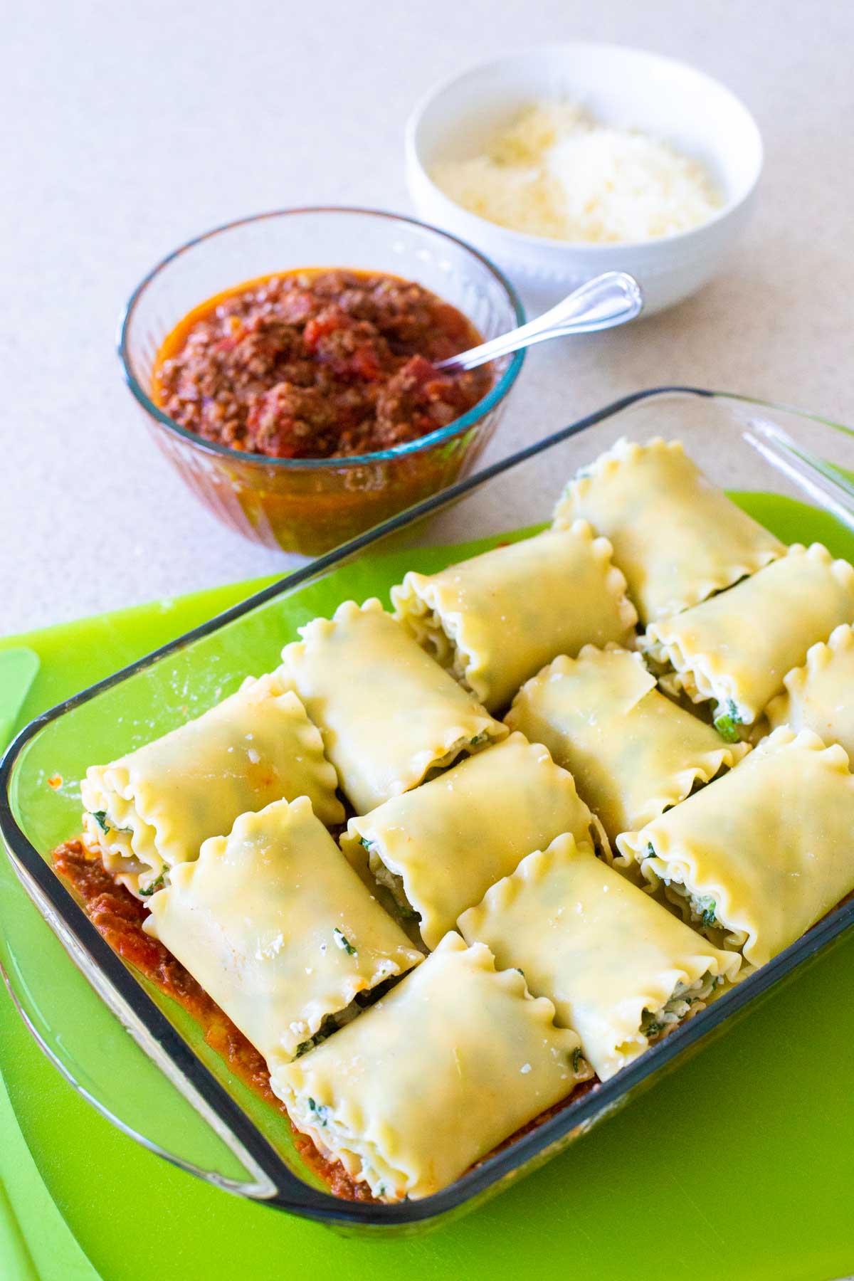 The baking dish has 12 lasagna roll-ups on a bed of tomato sauce.