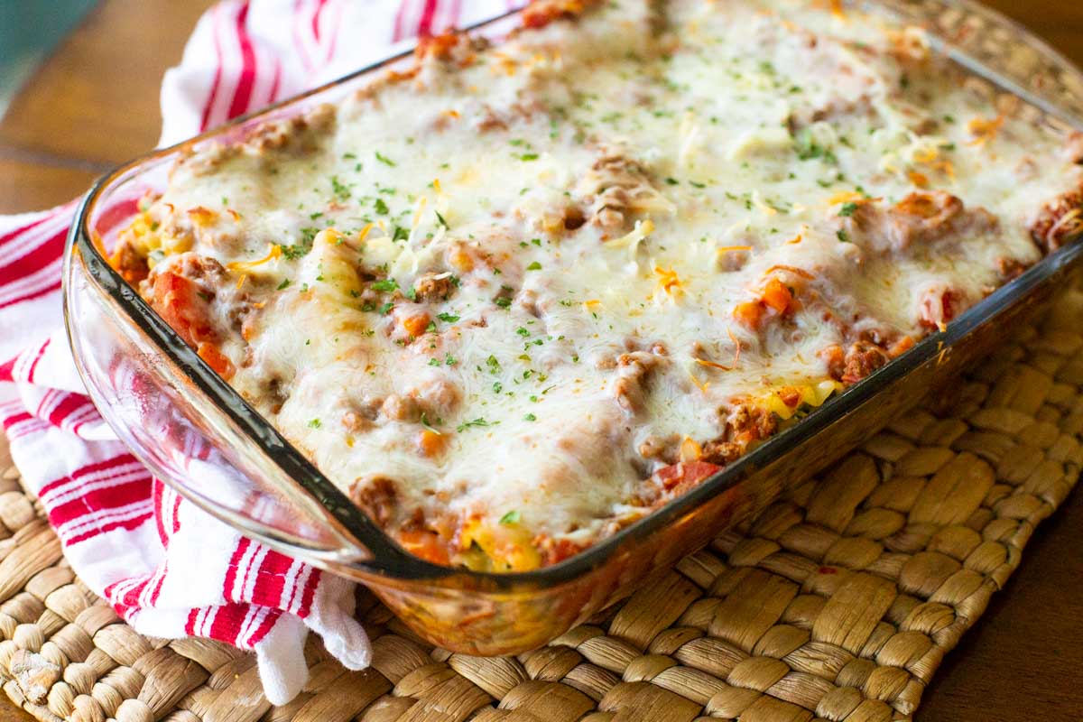 The baked lasagna roll-ups are cooling on a mat with a red and white striped towel.