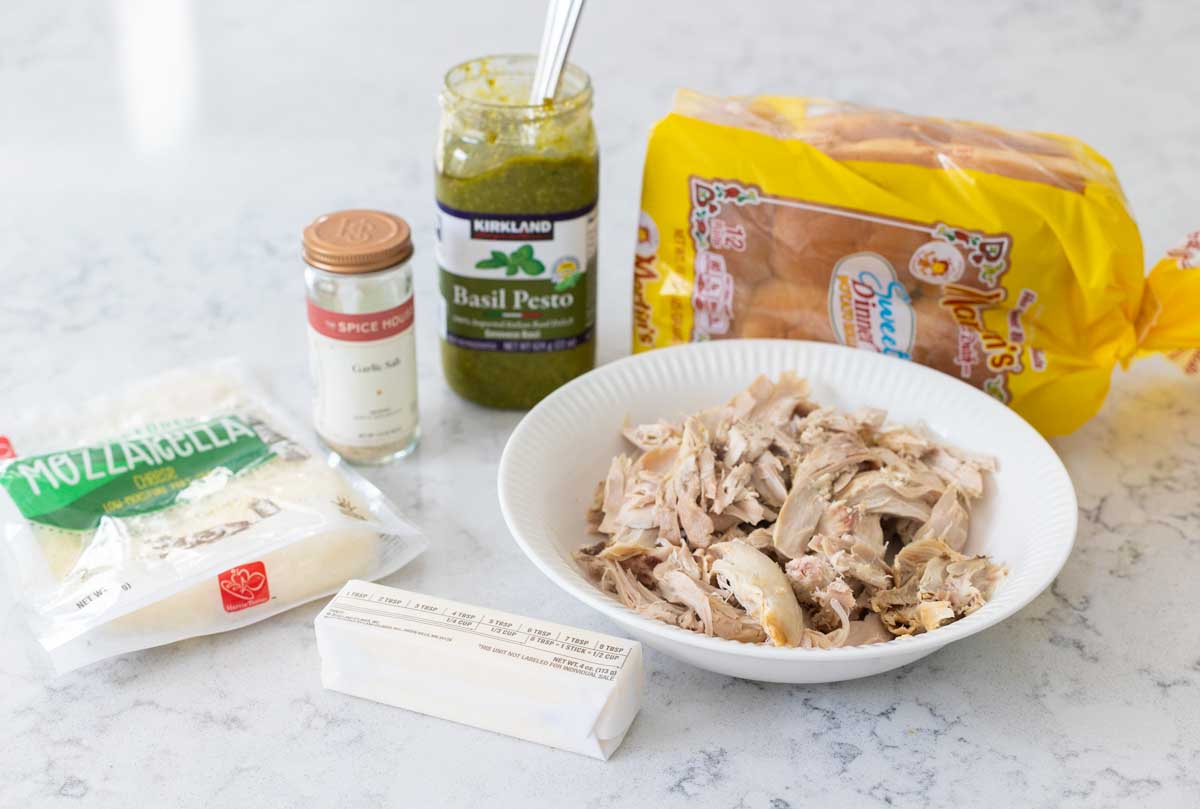 The ingredients to make pesto chicken sliders are on the counter.