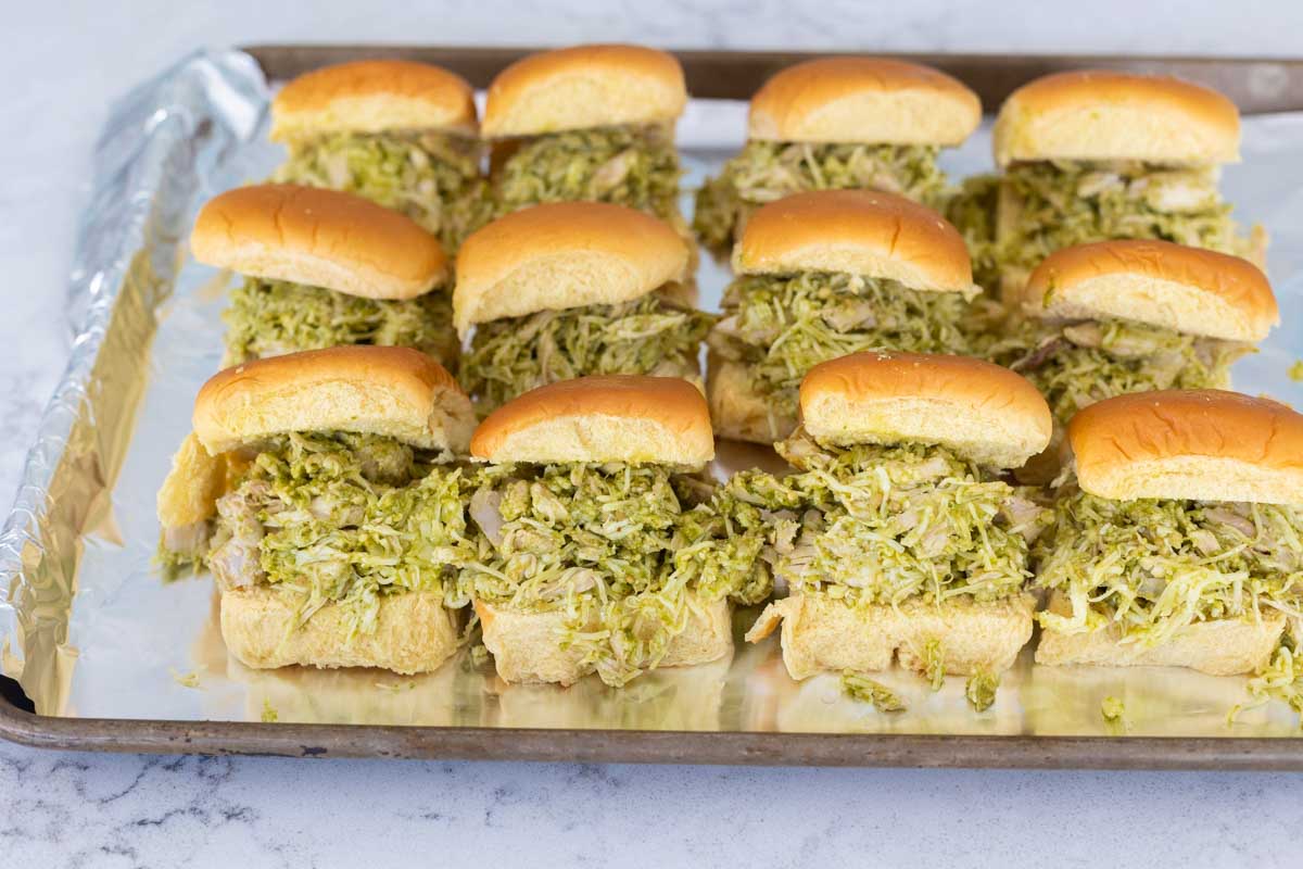 The sweet dinner rolls have been sliced in half and filled with prepared pesto chicken filling.