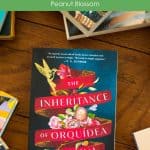 A copy of the book The Inheritance of Orquídea Divina sits on a table.