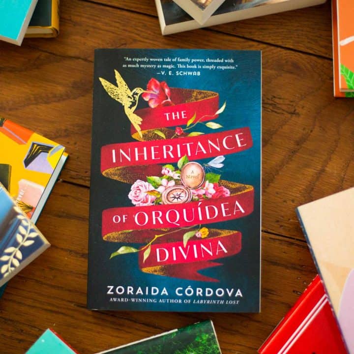 A copy of the book The Inheritance of Orquídea Divina sits on the table.