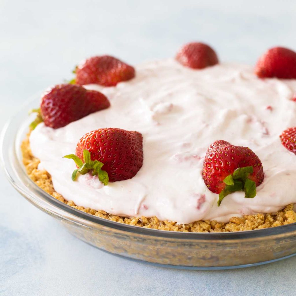 The no bake strawberry pie has a graham cracker crust and fresh strawberries on top. It is in a clear pie plate so you can see the crust.