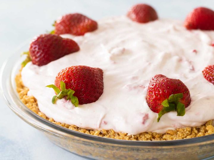 The no bake strawberry pie has a graham cracker crust and fresh strawberries on top. It is in a clear pie plate so you can see the crust.