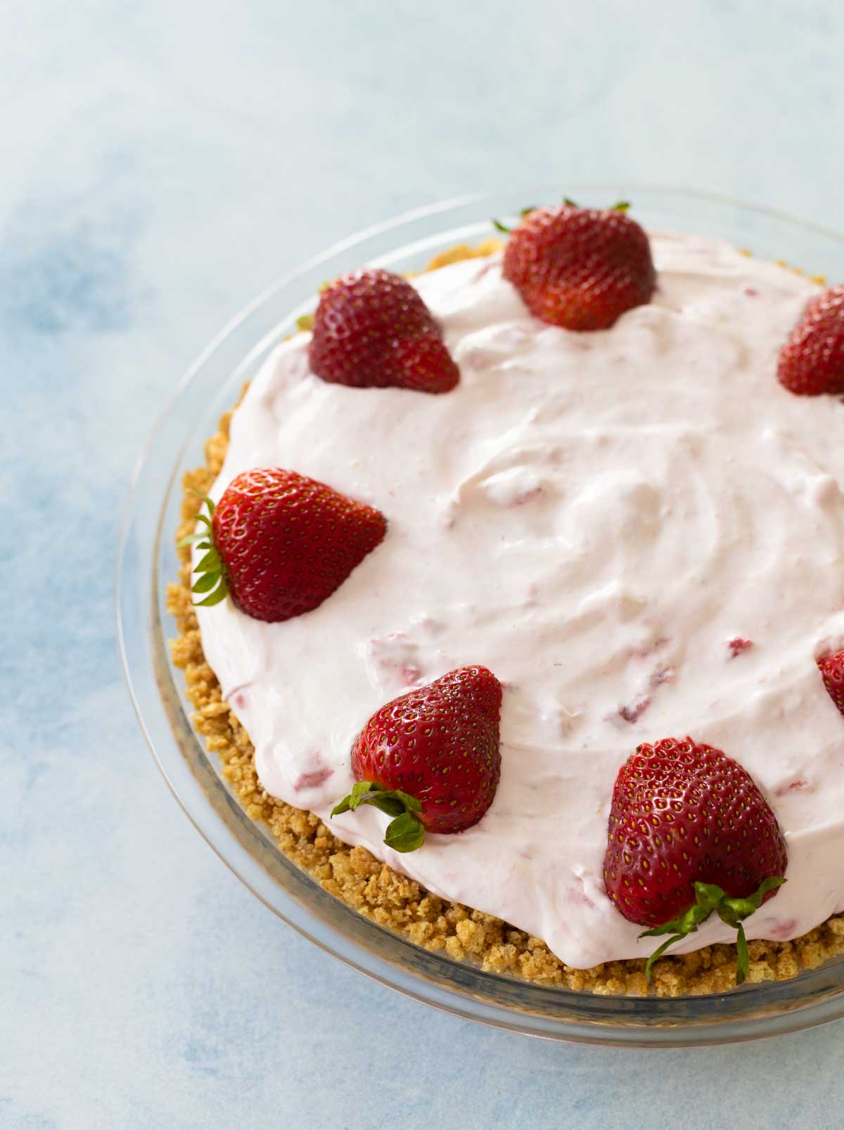 The garnished strawberry cream pie has fresh strawberries around the edge.