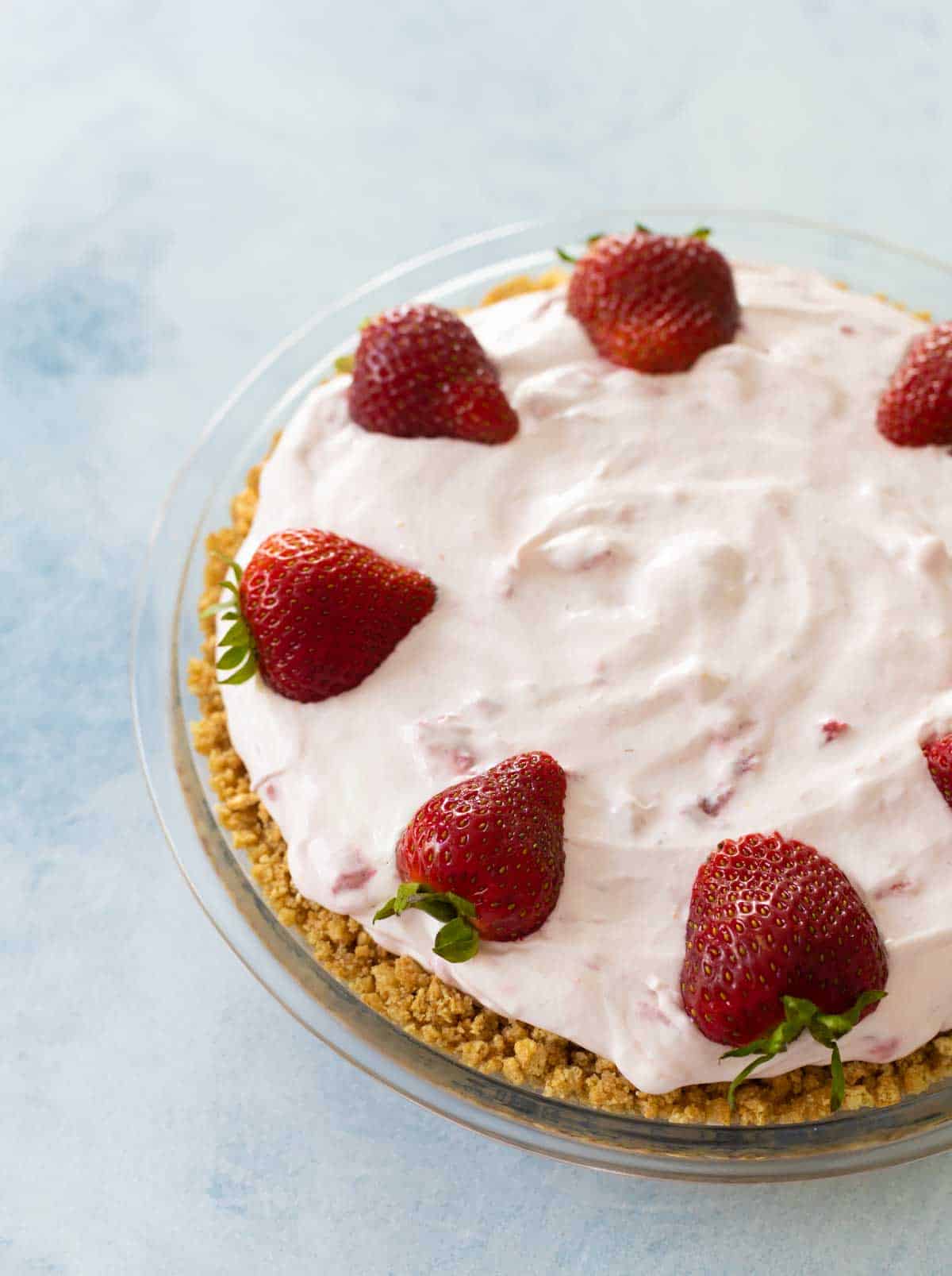 The garnished strawberry cream pie has fresh strawberries around the edge.