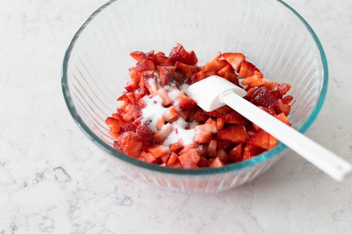 Chopped strawberries in a mixing bowl with sugar.