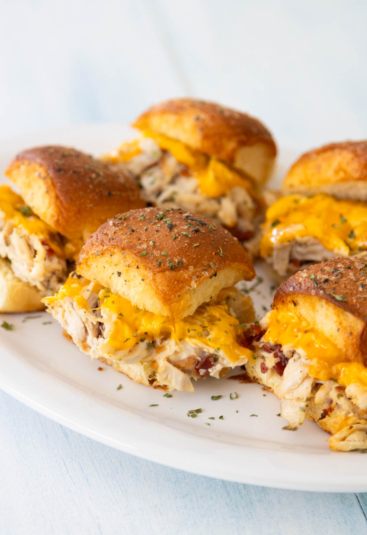 A white platter filled with chicken bacon ranch sliders shows the chicken filling and melted cheese.