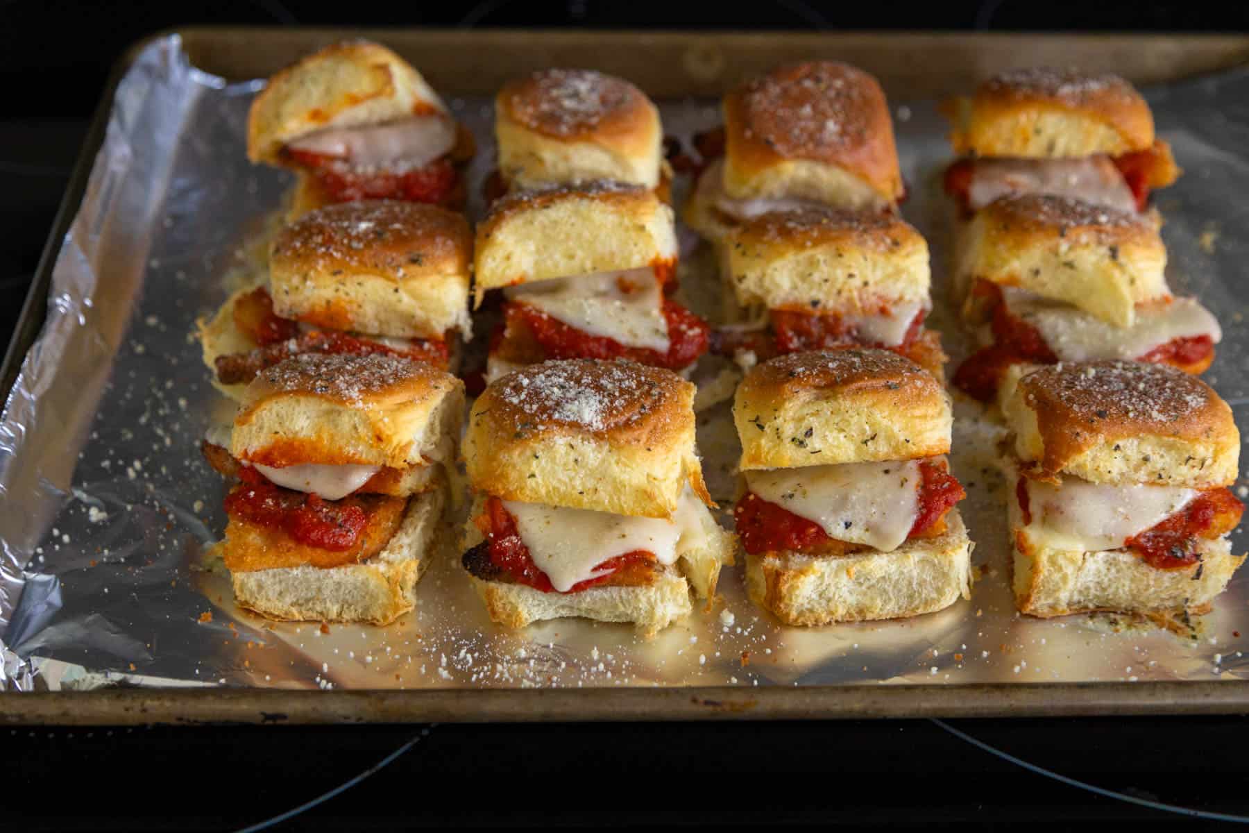 The baked sliders have just come out of the oven and the tops are golden brown and the cheese has melted.