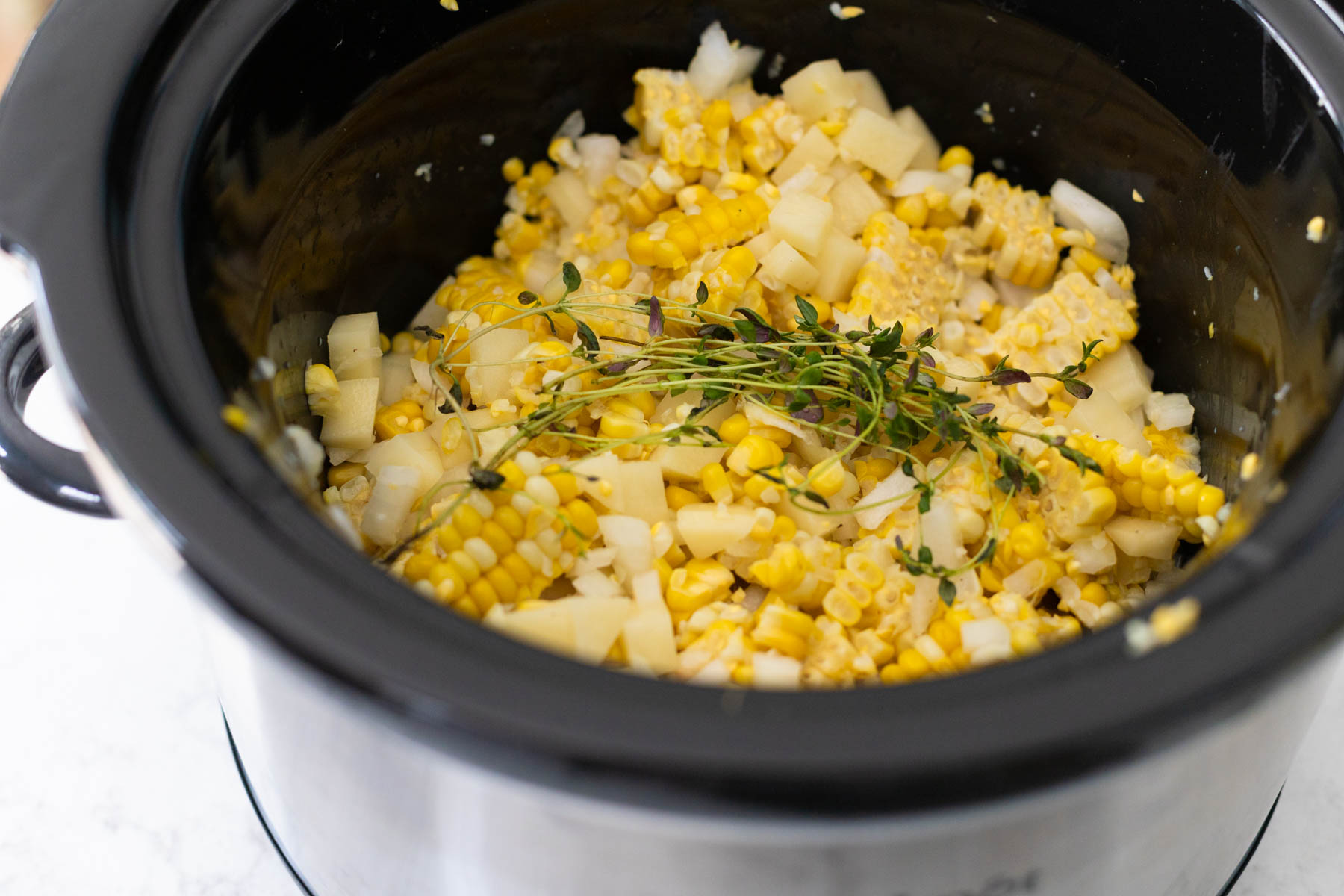 The corn, potatoes, onion, and fresh herbs are ready to cook in the slowcooker.