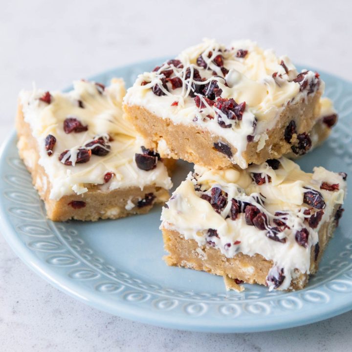 A blue plate has several squares of cranberry bliss bars ready to serve.