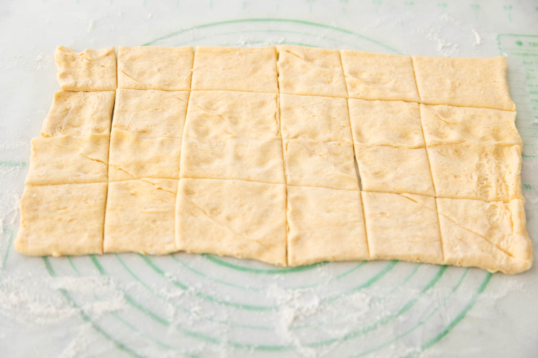 The dough has been rolled out and cut into 24 squares with a pizza cutter.