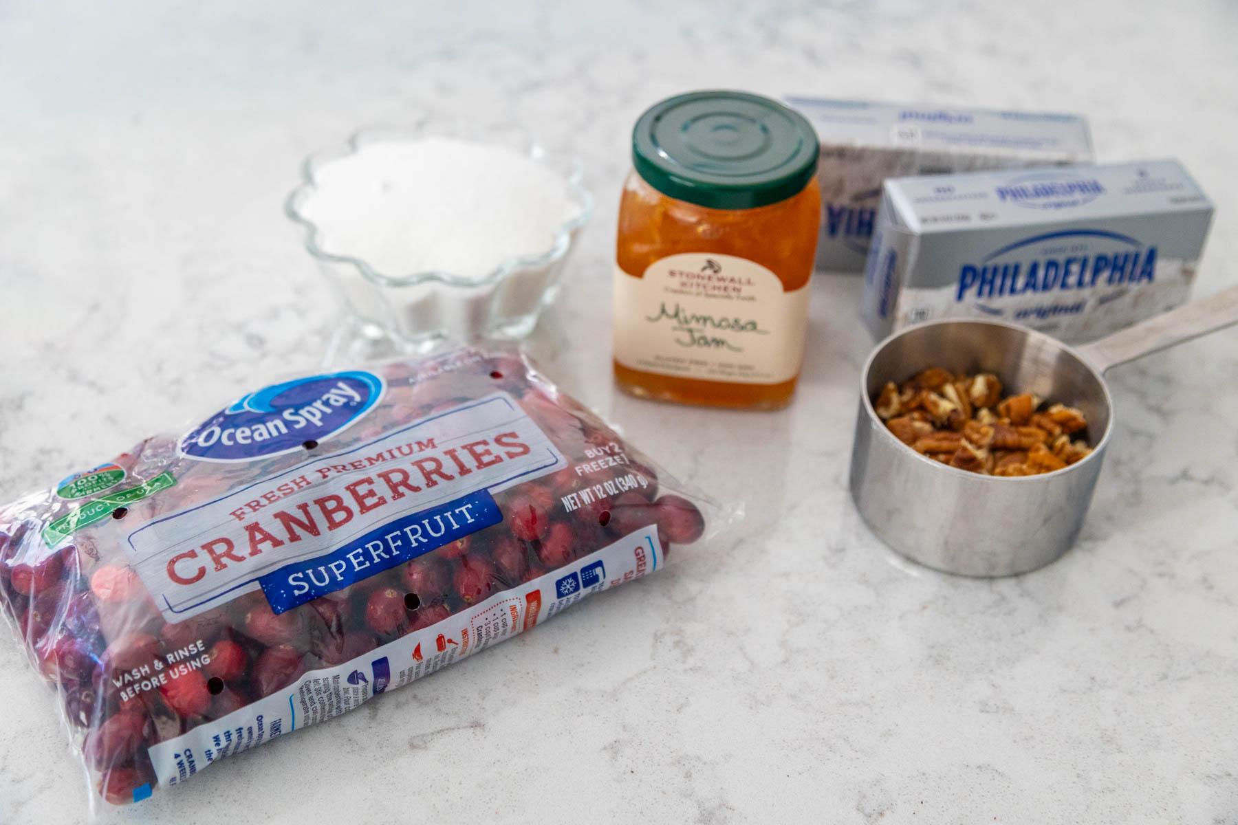 The fresh cranberries, jam, pecans, and cream cheese are on the counter.
