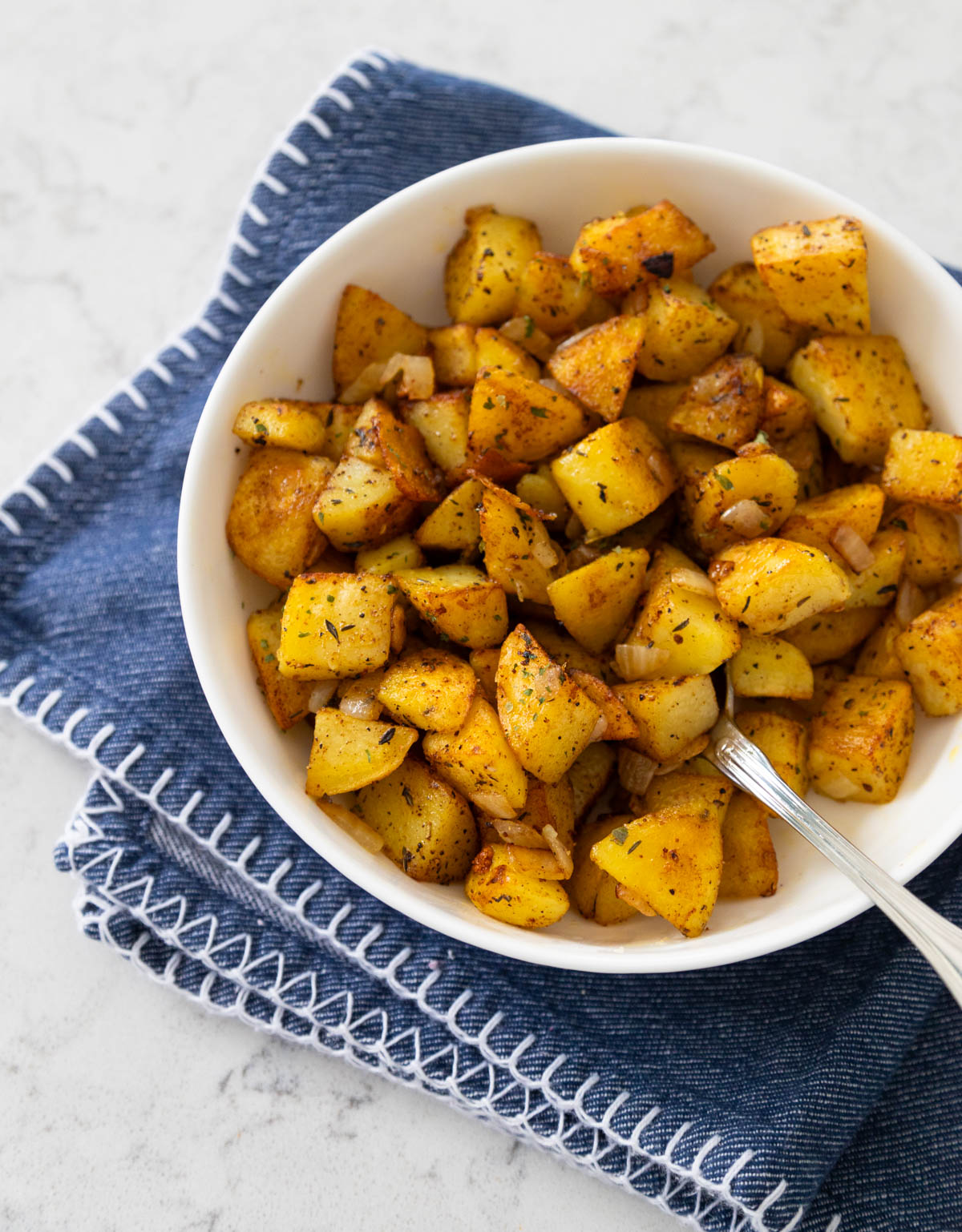The home fries are in a white bowl with a serving spoon.