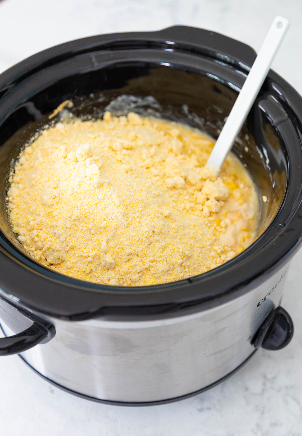 The dry cornbread mix has been added to the slowcooker.