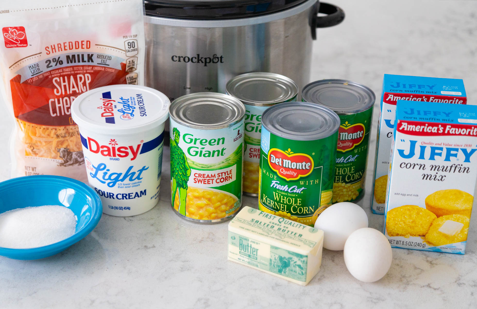 The ingredients to make Jiffy cornbread casserole are lined up on the counter next to the Crock Pot.