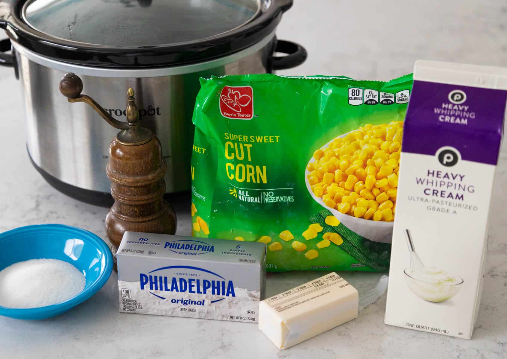 The Crock Pot is on the kitchen counter next to the ingredients to make creamed corn.