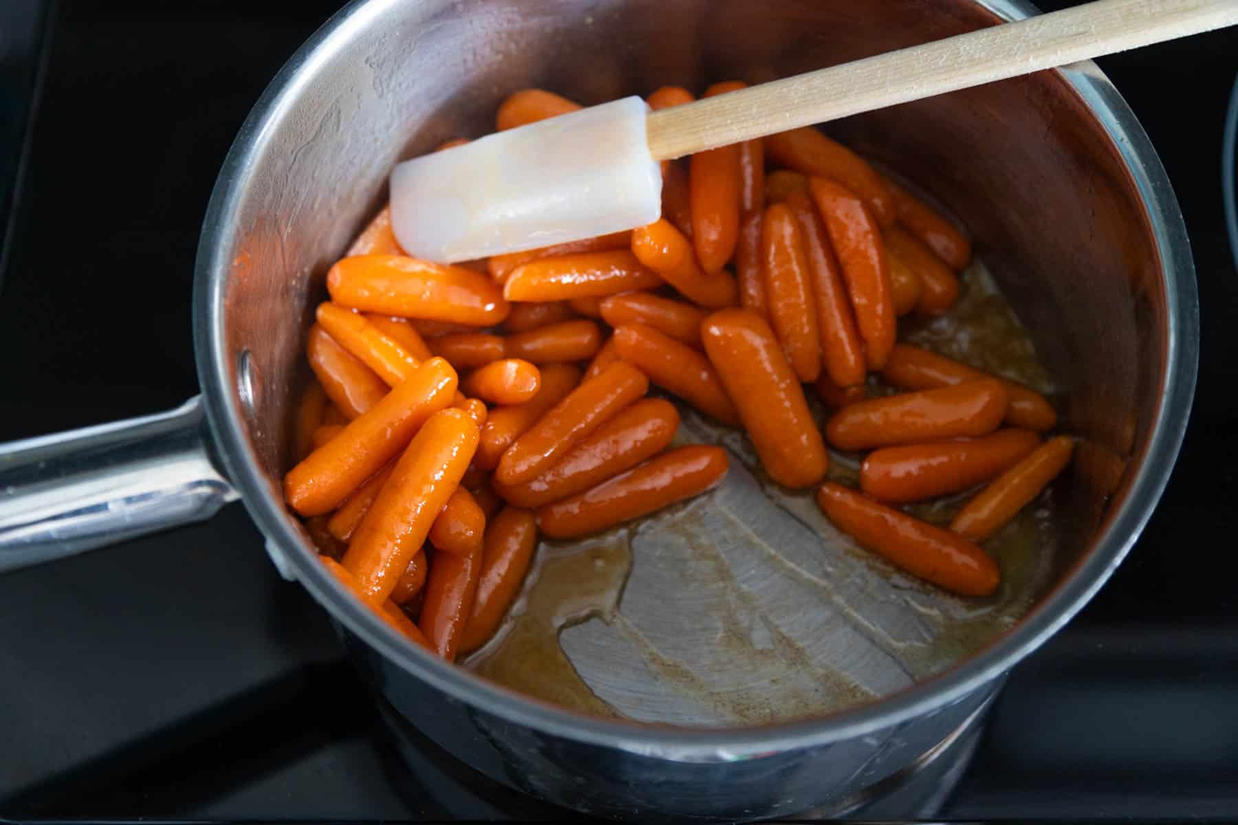 The brown sugar glaze has been thickened and reduced, the carrots have been pushed off to the side so you can see the texture at the bottom of the pan.