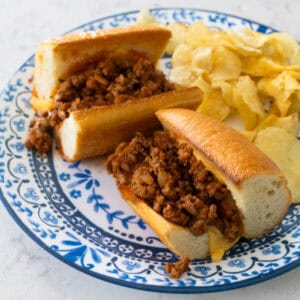 The baked ground turkey sloppy joes are on a blue plate with potato chips.