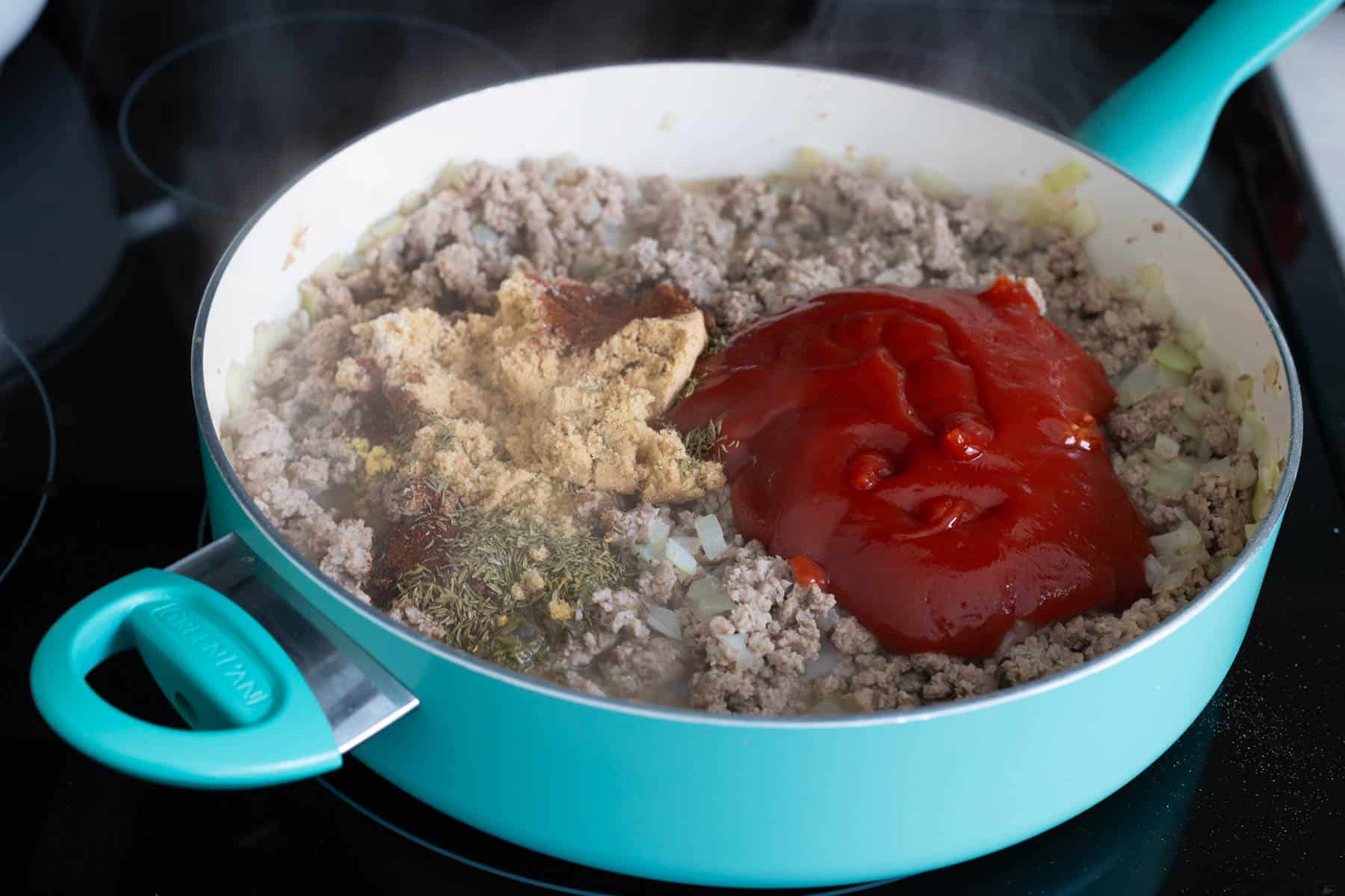 The seasonings and ketchup have been added to the skillet with the browned turkey.