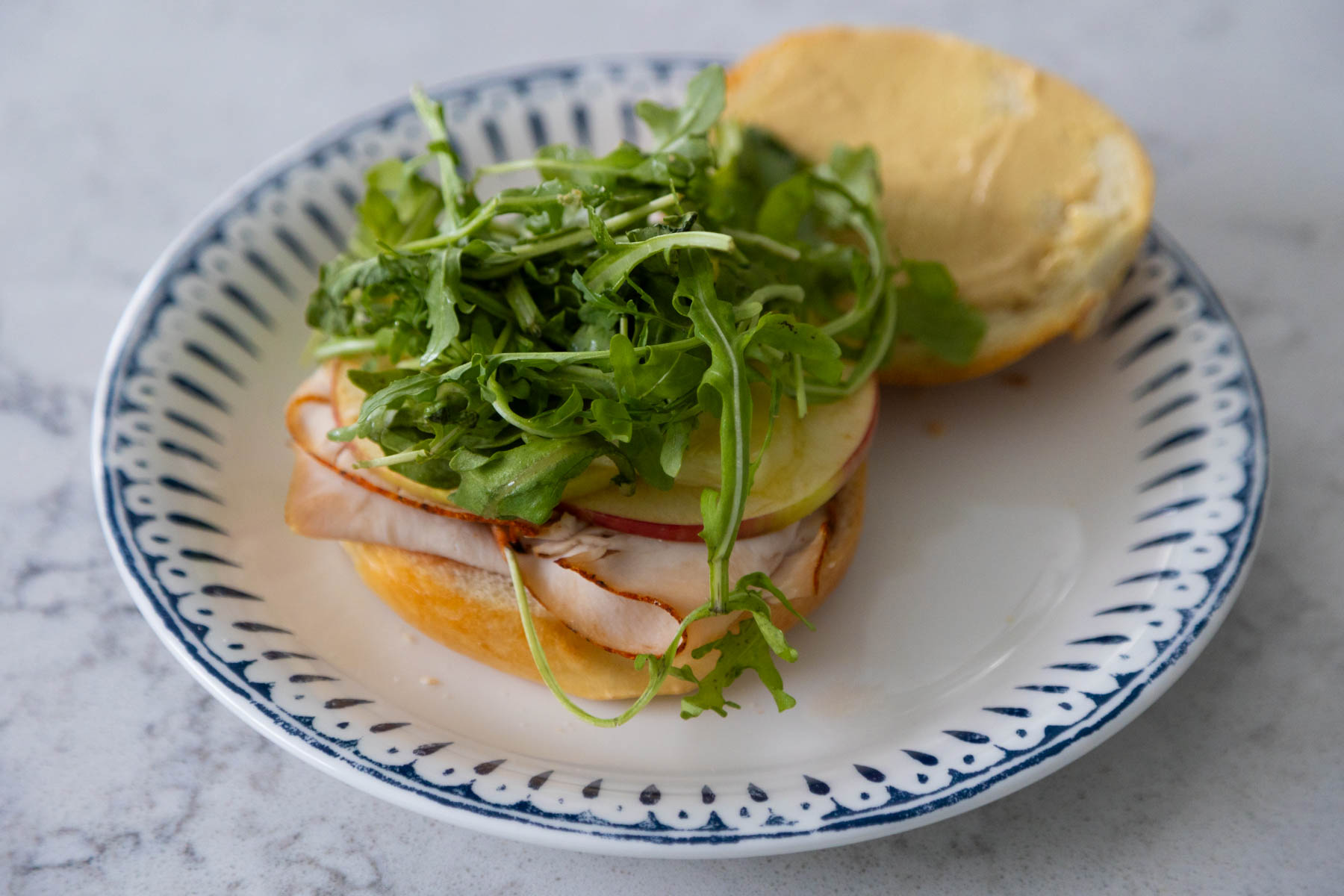 The sandwich has been spread with mustard and topped with arugula.