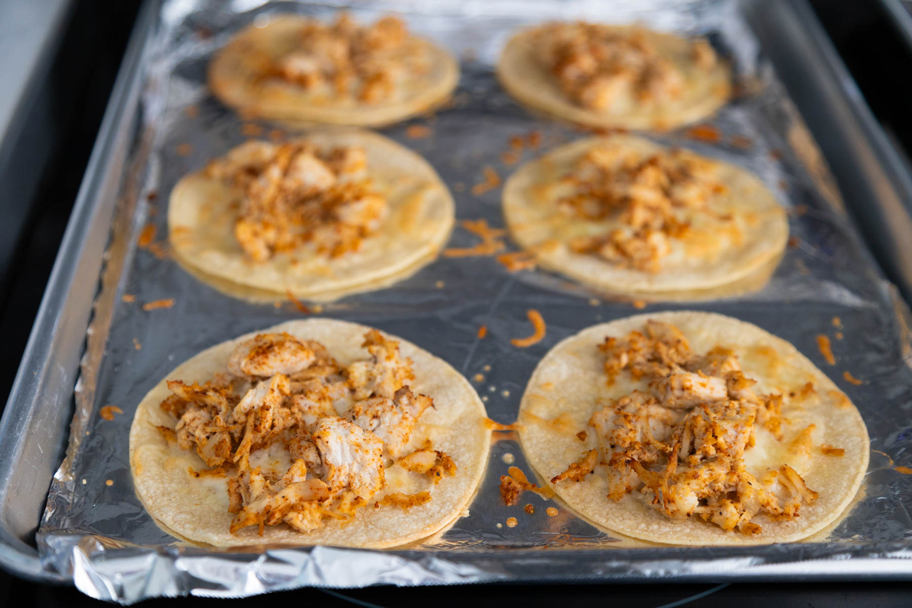 The chicken tacos have just come out of the oven, they are golden brown and the taco shells have slightly puffed up.