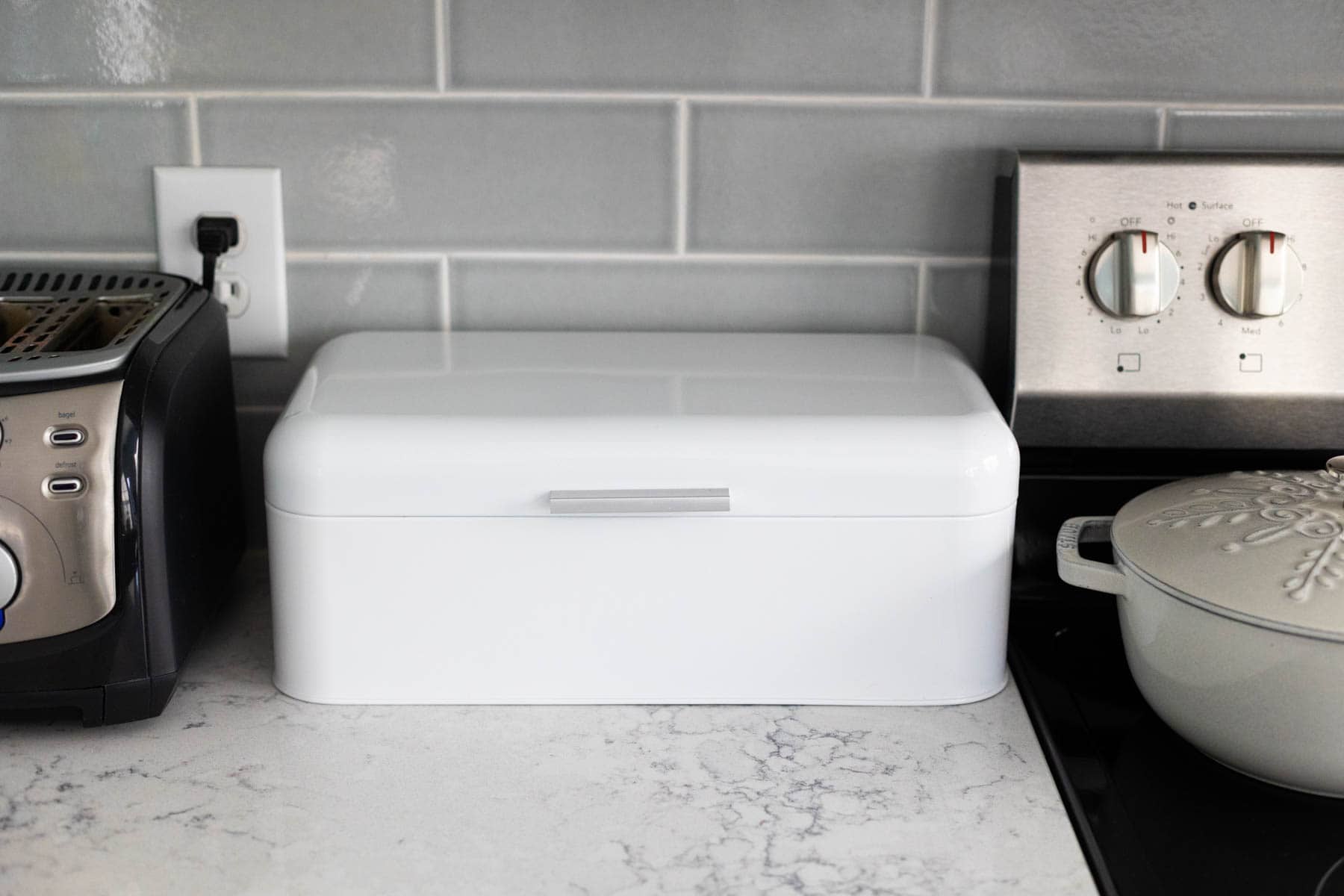 A white bread box is on the kitchen counter.