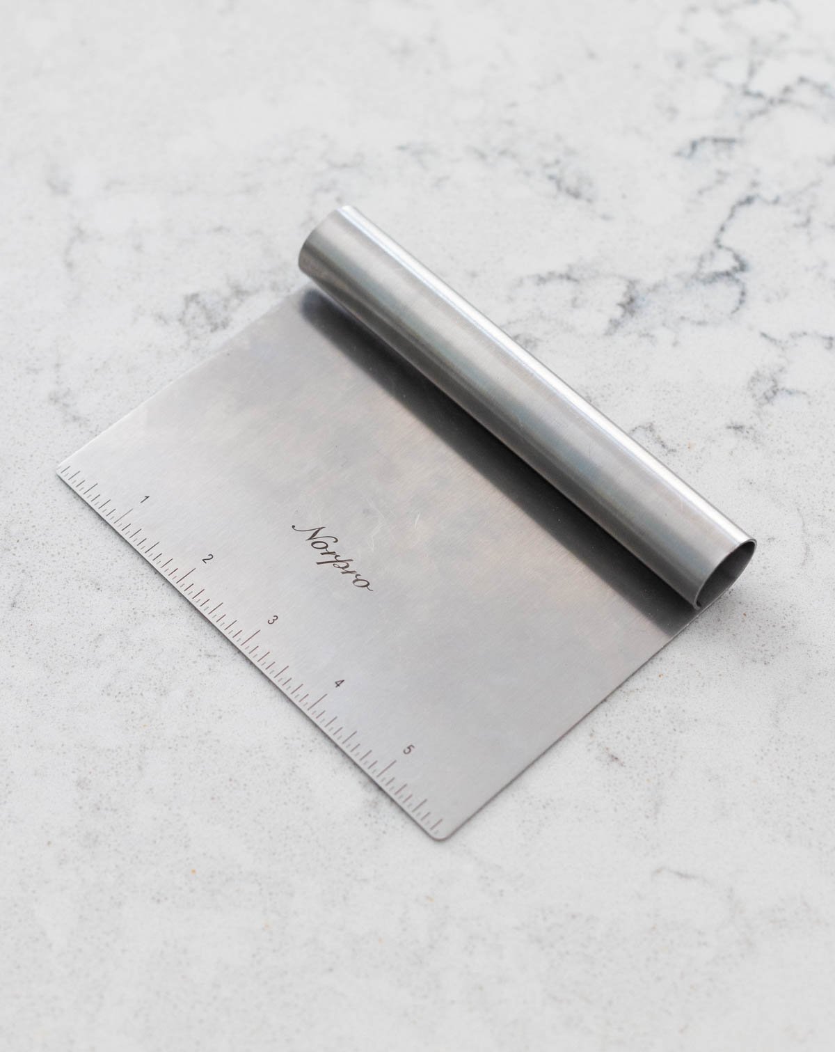 A metal dough scraper is on the counter.