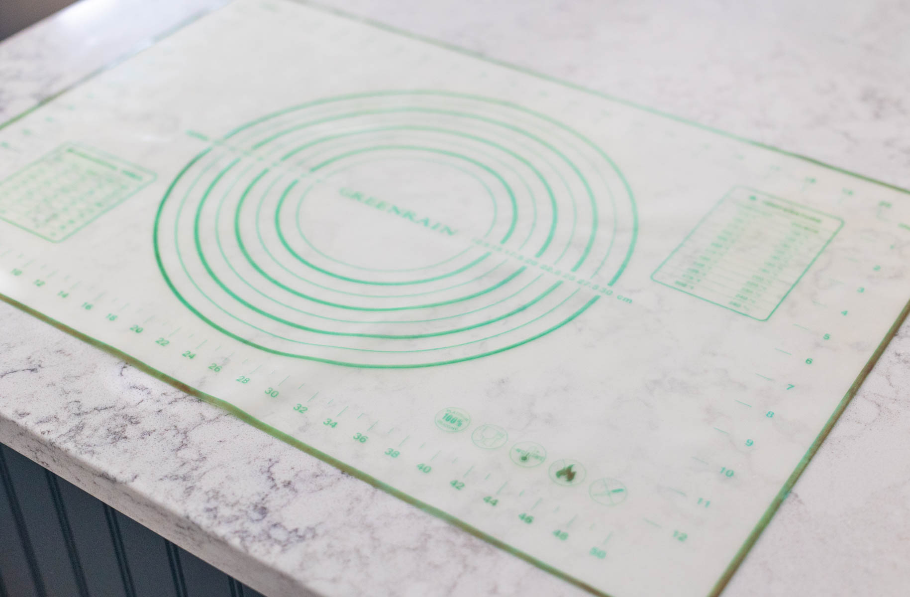A baking mat with ruler guides for measuring dough as you roll it out is on the counter.