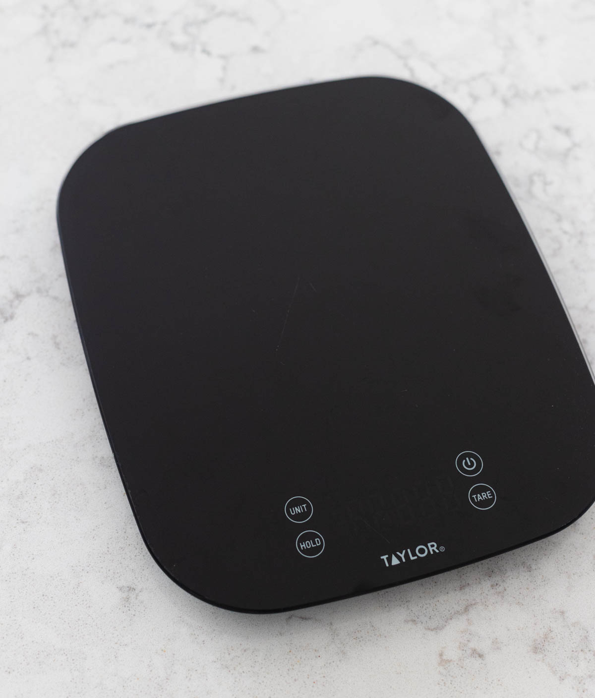 A black digital food scale is on the kitchen counter.