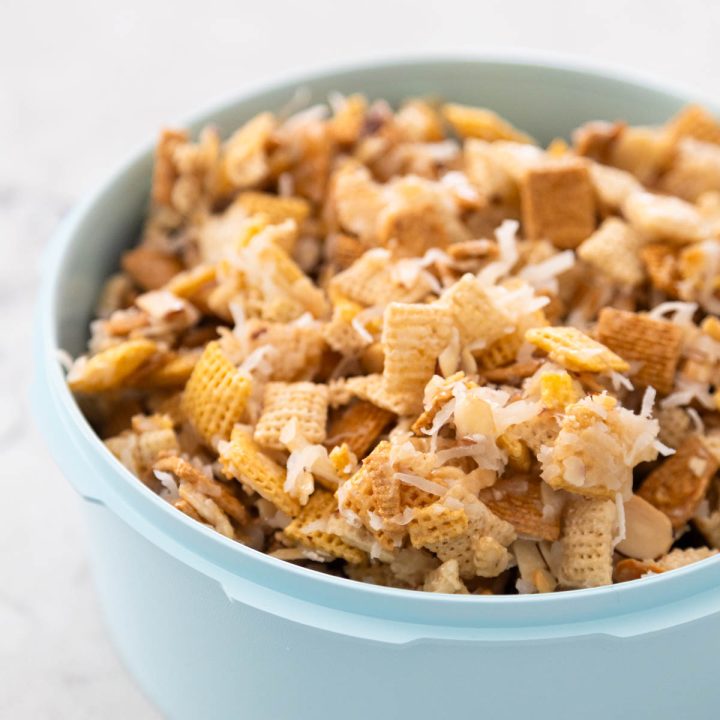 A blue container is filled with a coconut Chex Mix with toasted almonds.