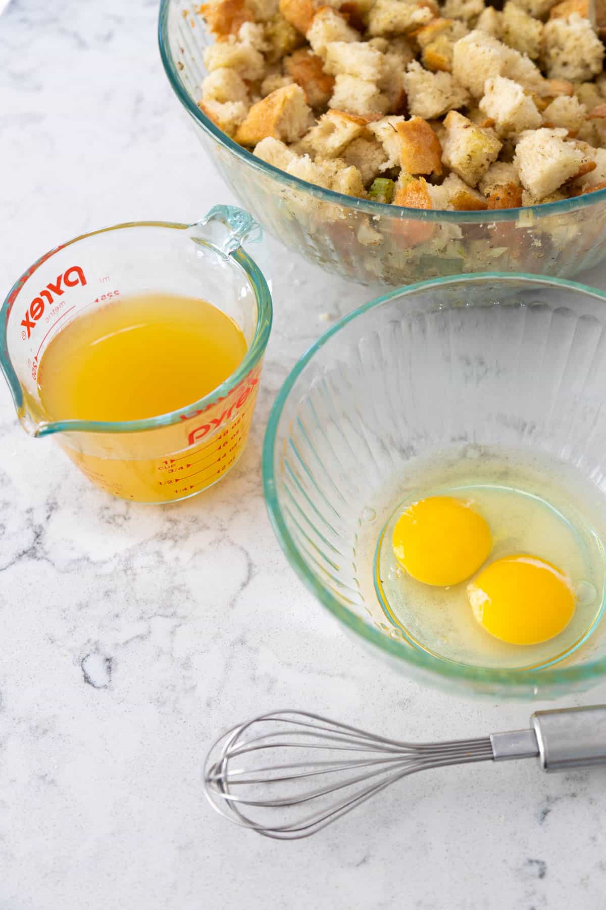 The stuffing is about to be moistened by chicken stock and eggs which have been prepped in small bowls.