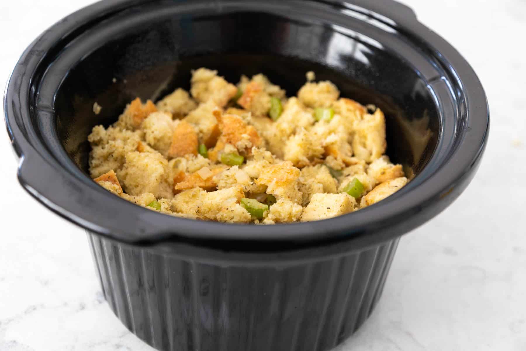 The stuffing mixture has been spooned into the bowl of a slowcooker.