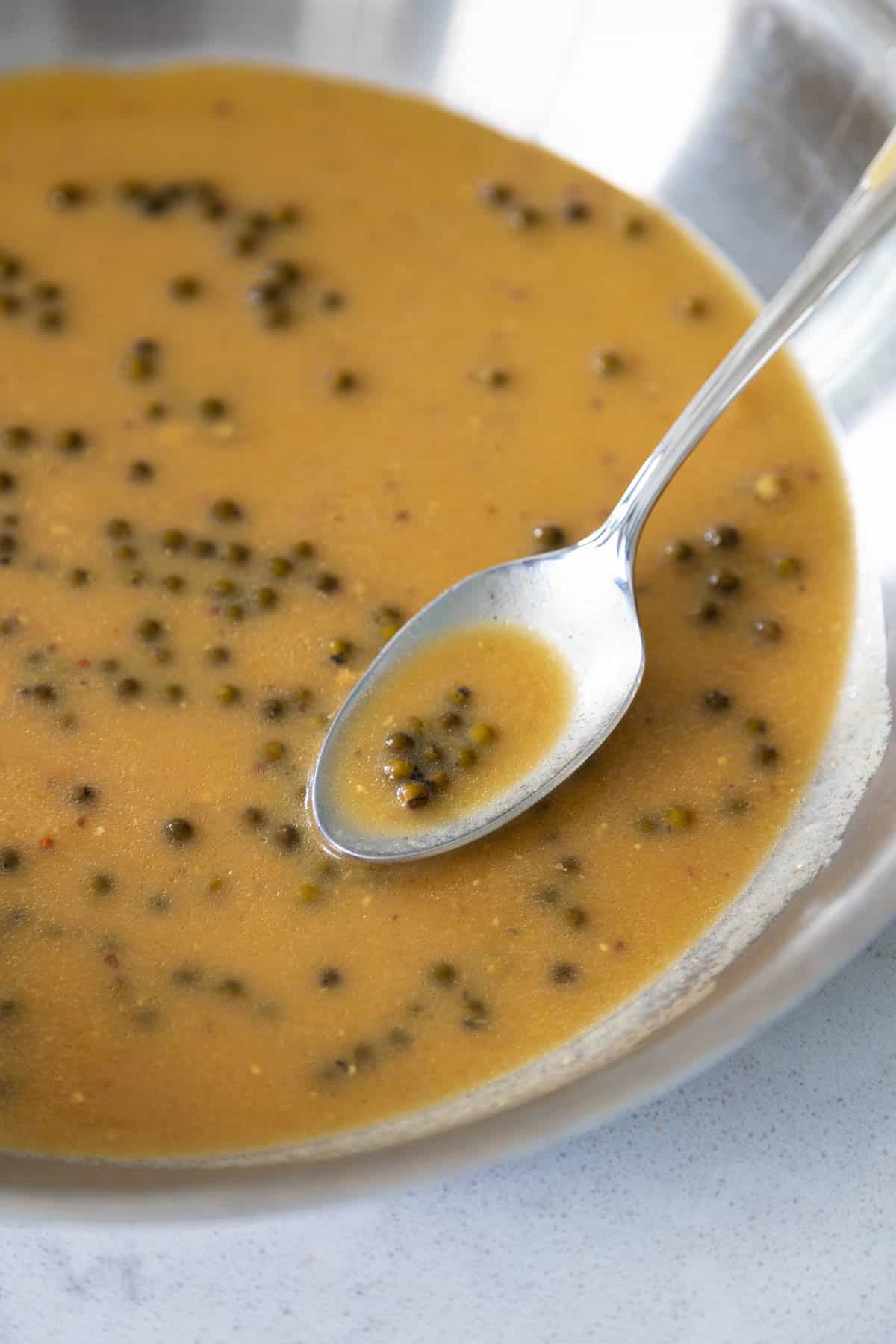 The skillet has the sauce being stirred by a spoon.